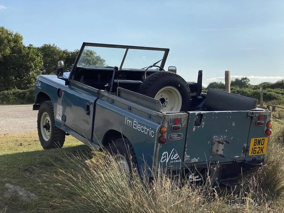 Classic Land Rover converted to electric, parked outdoors with spare wheel visible.